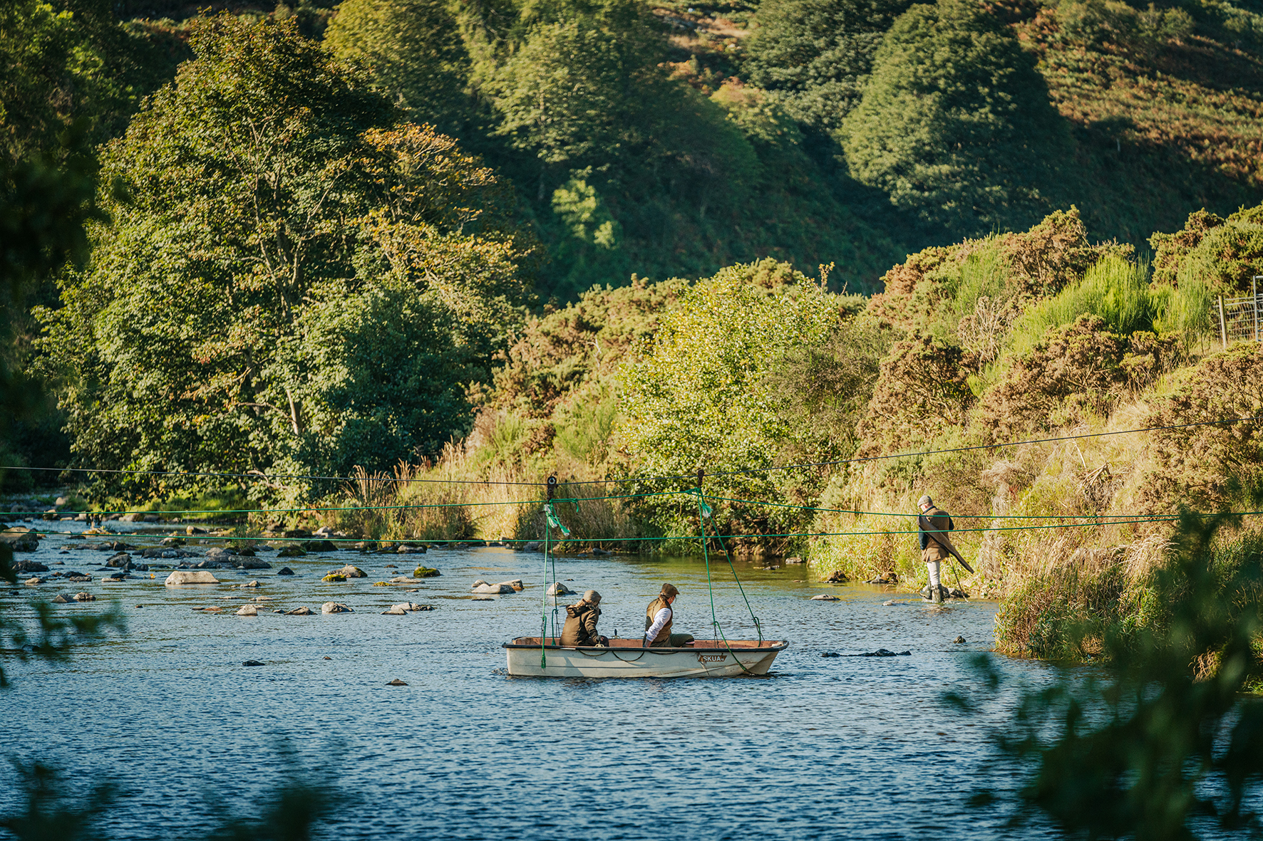 Wide shot of shooting party with boat crossing river at Primrosehill