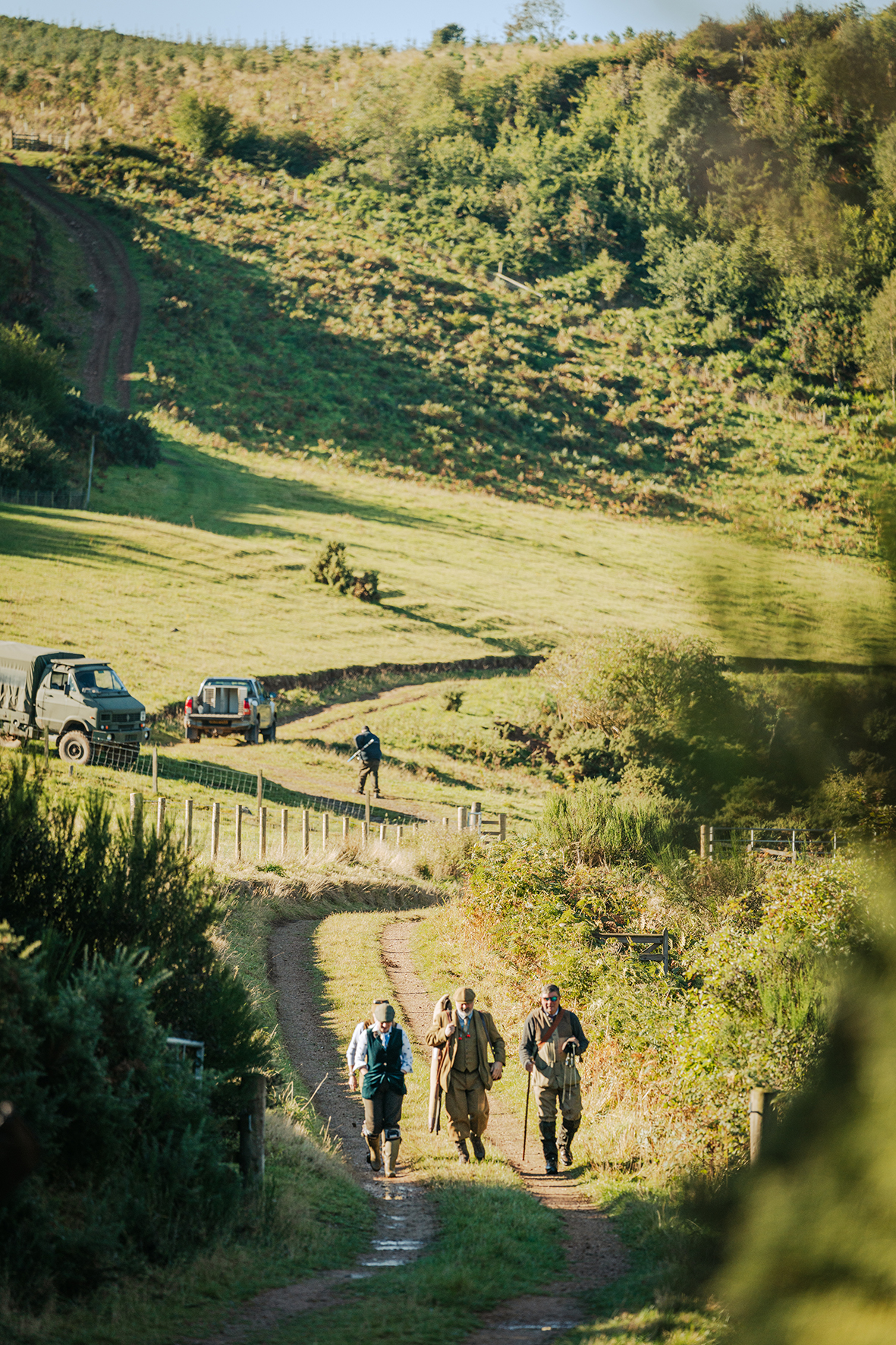 Shooting party walking down country path in autumn countryside