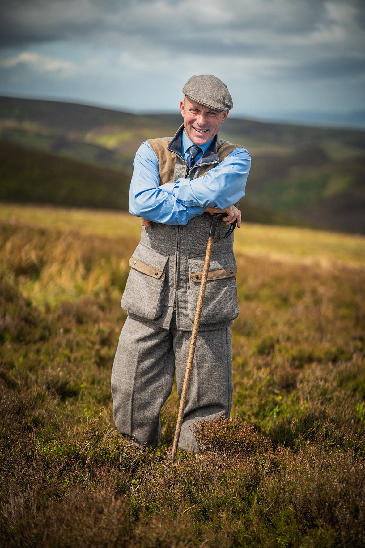 Full-length portrait of Robbie Douglas-Miller on moorland with walking stick